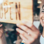 Small business owner places her open sign in the front door.