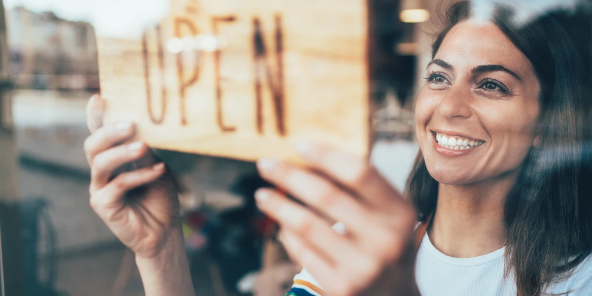 Small business owner places her open sign in the front door.